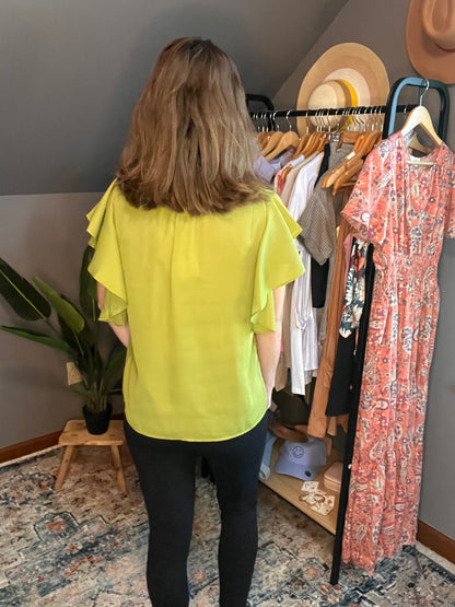 chartreuse blouse with ruffle sleeves paired with black pants